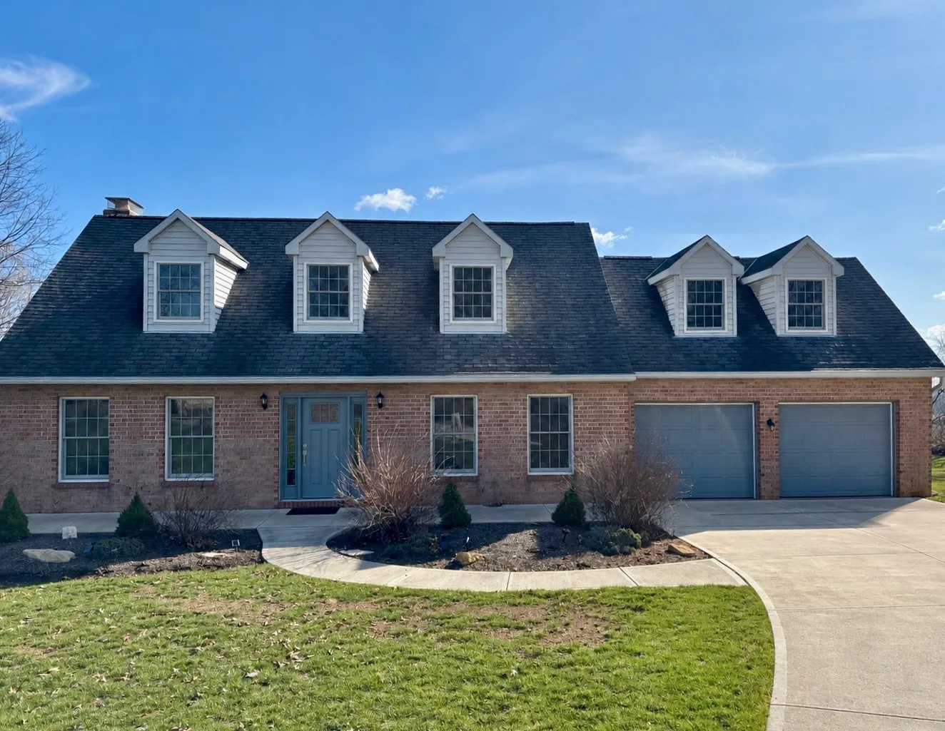 Brick Cape Cod home with five dormers and a new dark asphalt shingle roof by West Penn Exteriors